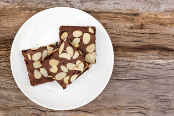 Homemade brownies sliced on white plate over wooden table. Top view with copy space.