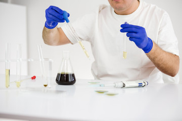 Scientist working with pharmaceutical cbd oil in a laboratory with glass equipment