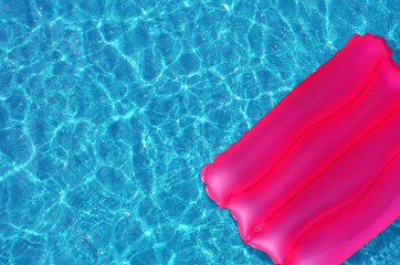 Pink inflatable pillow on the surface of the water in the pool.