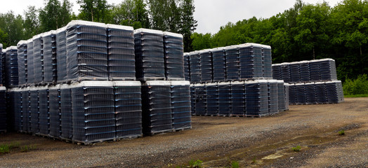 Finished products of clean bottles are packed in pallets. Racks with bottles are in  abandoned area near  glass factory near  forest.