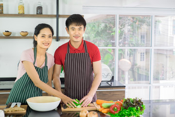 Asian young couple. Are standing smiling cooking in the kitchen at home. prepare salad for food...
