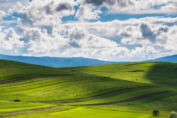 Sunlights breaking trough the dramatic clouds over green meadow  at springtime, 