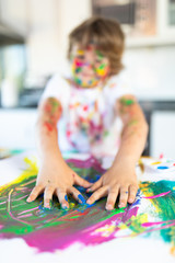 Cheerful child painting with colorful paint