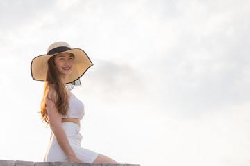 Asian young woman wearing white dress smile enjoy with summer vacation on pier on beach feeling so happiness and cheerful,Travel in tropical beach in Thailand,vacations and relaxation Concept