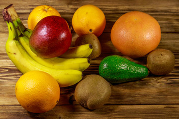 Assortment of tropical fruits on wooden table. Still life with bananas, mango, oranges, avocado, grapefruit and kiwi fruits