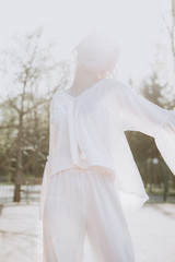 light, sunny, emotional photo of an attractive blonde girl who poses for a photo under bright sunlight dressed in light white clothes