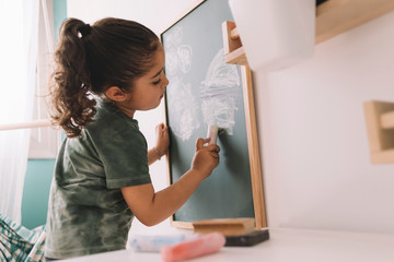 little girl drawing on a chalkboard at her room