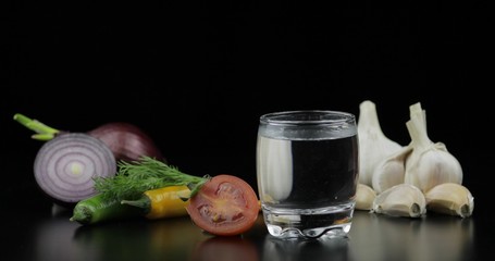 Alcohol drink vodka in shot glass. Background with vegetables