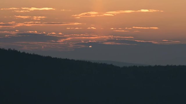 Superzoom plan timelapse sunset through sunset clouds in orange tones. Low key