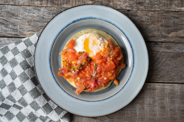 Mexican food: Fried egg rancheros with sauce and corn tortilla