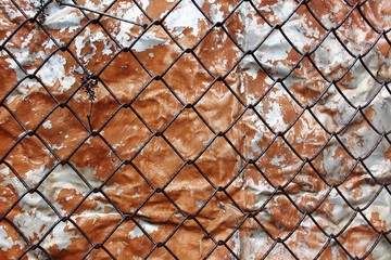 Old rusty grid on the background of painted peeling steel wall