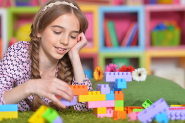 Curly girl playing with colorful plastic blocks