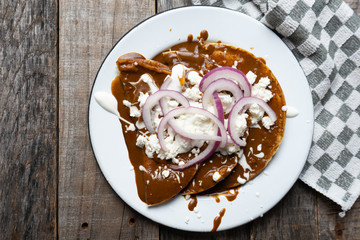 Mexican food: Mole sauce enchiladas with cream and fresh cheese