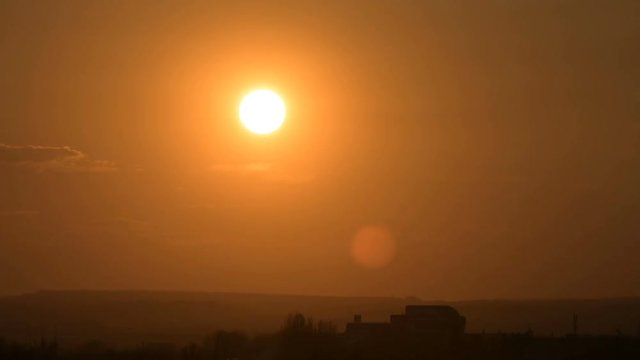 Superzoom plan timelapse sunset with a clear sky in orange tones on a flat horizon