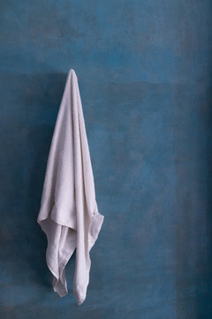 White towel hanging on ocean blue cement wall after shower.