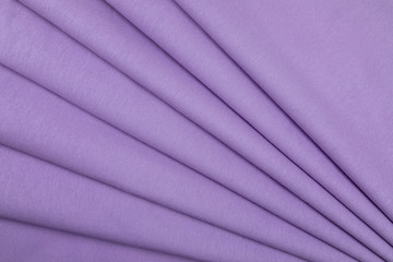Rough cotton fabric structural with development of violet color. Large strings of a basis of material. Fabric is put by accurate geometrical folds