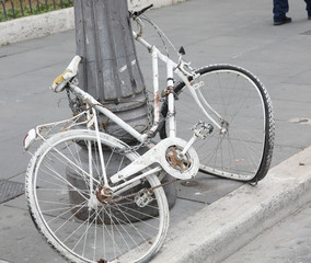 white bicycle abandoned on a light pole