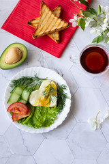 Fried eggs with lettuce, cucumber and tomato slices on a light background
