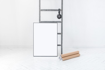 Pusta ramka na plakat oparta o drabinę w minimalistycznie białym pokoju. Zwinięte plakaty położone na podłodze. - obrazy, fototapety, plakaty