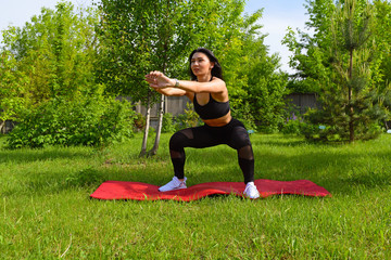 Athletic young crouches on the red carpet in a green Park.