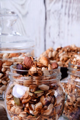 Homemade granola with different nuts and seeds in glass jars against the white background