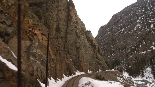train tracks looking backwards through rocky mountain pass with river
