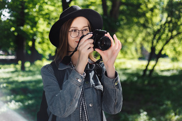 attractive young girl in a hat take picture on camera outdoors