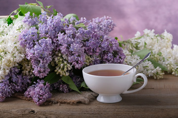 Obraz na płótnie Canvas Bouquet of lilac, a cup of tea on a wooden table.