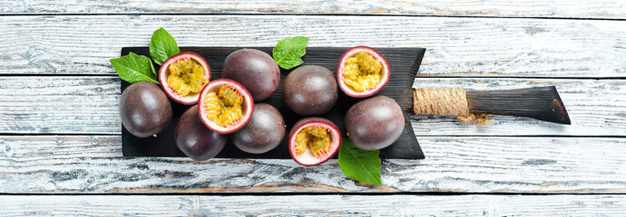 Passion fruits with a leaf on a white wooden background. Tropical Fruits. Top view. Free space for text.