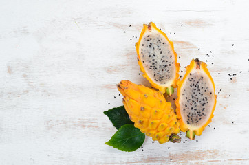 Yellow Dragon Fruit on a white wooden background. Pitahaya Tropical Fruits. Top view. Free space...