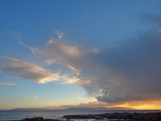 Fototapeta na wymiar Sunset clouds over ocean, Galway bay, Burren mountains in the background. Atlantic ocean. Ireland.