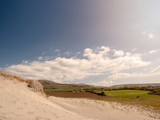 Sand dunes in Burren national park, Ireland. Cloudy sky, Green field.