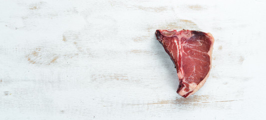 T-bone steak on a white table. Raw Steak Top view. Free space for text.