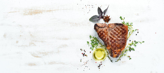 Medium rare Grilled T-Bone Steak on a white table. Top view. Free space for text.