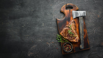 Grilled T-Bone Steak on the old table. Top view. Free space for text.