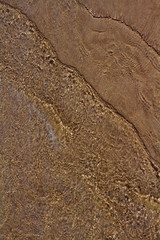 sand lying in the water and the waves going to the shore.