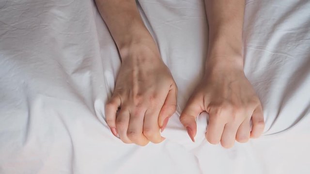 girl's hands on the bed in the bedroom against the white sheet