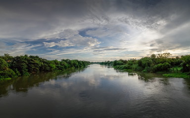 Fototapeta na wymiar Panorama river view evening of Mae Klong river with soft rain and cloudy sky background, Ban Pong District, Ratchaburi, Thailand.