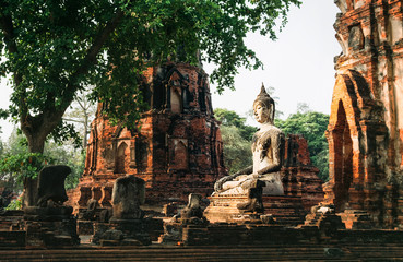 Meditating Buddha sculpture in the middle day sun light rays in ancient Ayutthaya city, Thailand.