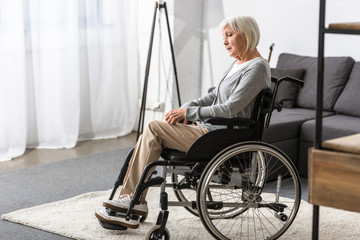 disabled senior woman sitting in wheelchair and looking away