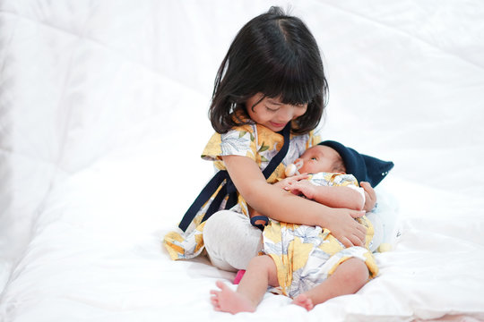 Asian elder sister hug her newborn baby sister with love. family concept.  