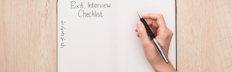 panoramic shot of recruiter writing in notebook with exit interview checklist lettering