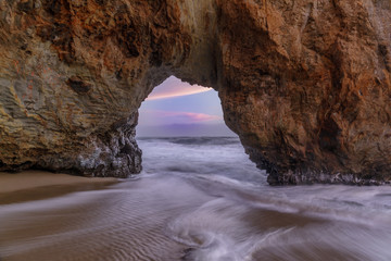 Sunset Through Sea Arch in Hole in the Wall beach. Bonny Doon, Santa Cruz County, California, USA.