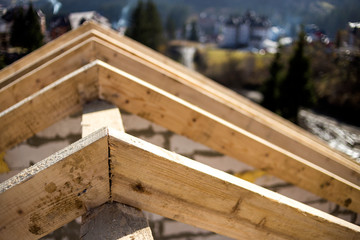 Fototapeta na wymiar Close-up detail of roof frame of rough wooden lumber beams on background of misty mountain landscape in ecological area. Building, roofing, construction and renovation concept.