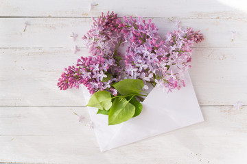 Envelope with lilac on wooden white background