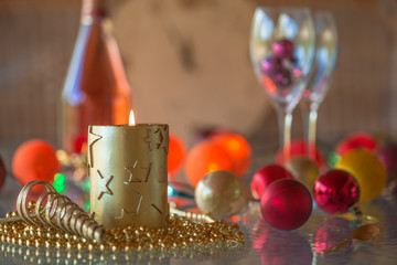 Christmas and New year concept: burning candle, christmas decorations and lights, bottle of champagne and glasses