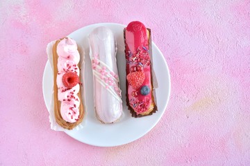 Beautiful traditional French eclairs cake with creative pink decor and fresh berries on pink...