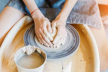 Hands working with clay at potter wheel