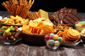 Salty snacks. Pretzels, chips, crackers in wooden bowls on table