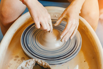 Hands working with clay at potter wheel